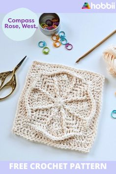 the crochet square is next to some scissors and yarn on top of it