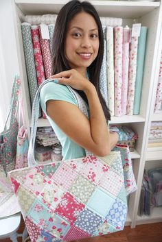 a woman holding a multicolored patchwork tote bag in front of a bookcase