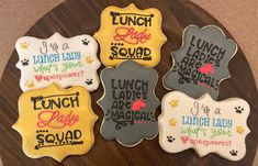 four decorated cookies with different sayings are on a wooden platter that says lunch lady, lunch lady, lunch lady, lunch lady, lunch lady, lunch lady, lunch lady, lunch lady, lunch lady