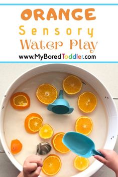 oranges and water play in a bowl with spoons on the side for kids to use