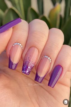 a woman's hand with purple and pink nail polishes on her nails, holding up