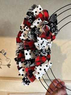 a person holding up a red and black bow with white polka dots on the top