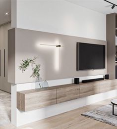 a modern living room with white walls and wood flooring, large television on the wall