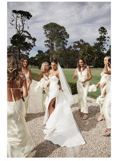 the bride and her bridal party are walking down the path in their white dresses