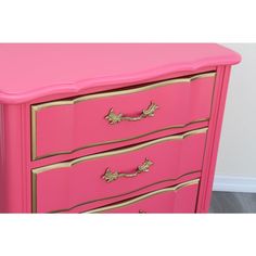 a pink dresser with gold trim and drawers