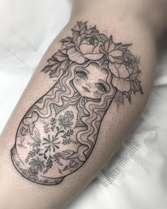 a woman's leg with flowers and a vase tattoo on her thigh, done by the artist