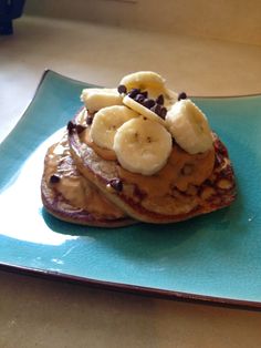 pancakes topped with bananas and chocolate chips on a blue plate