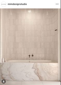 a bathroom with white marble walls and flooring, along with a bathtub in the middle