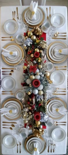 a christmas table setting with silver and gold plates, red napkins and white dishes