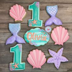 decorated cookies are arranged in the shape of mermaid tailes and seashells for first birthday