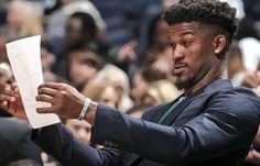 a man in a suit reading a piece of paper while standing next to an audience