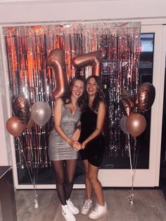 two women standing next to each other in front of balloons