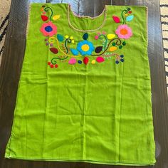 a green bag with colorful flowers on it sitting on top of a wooden floor next to a rug