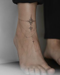 a woman's foot with a cross tattoo on the bottom of her left ankle