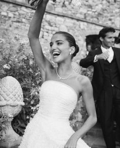 a woman in a wedding dress is holding her hand up to the sky and smiling