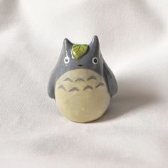 a ceramic animal figurine with a green leaf on it's head sitting on a white surface