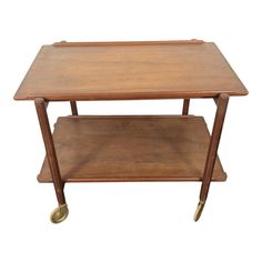 a small wooden table with wheels on the bottom and one shelf below it, against a white background