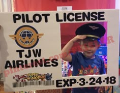 a young boy wearing a pilot's hat and holding up a sign