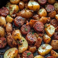 cooked potatoes and sausages in a pan with herbs sprinkled on the side