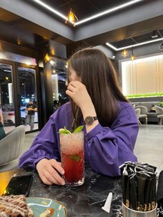 a woman sitting at a table with a drink