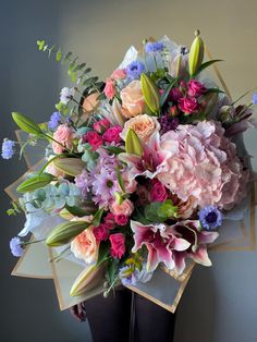 a large bouquet of flowers on display in front of a gray wall with blue and pink accents