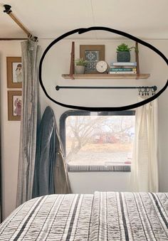 a bed sitting under a window next to a shelf with books on top of it