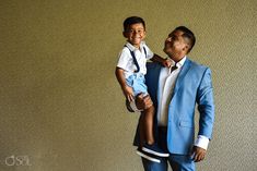 a man in a blue suit holding a little boy on his shoulders and smiling at the camera