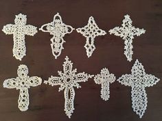 six crocheted crosses sitting on top of a wooden table