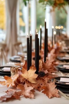 the table is set with candles and leaves