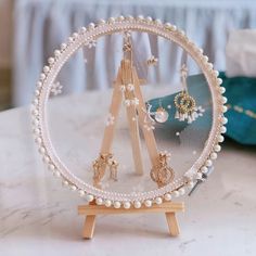 a white table topped with a wooden stand filled with pearls and gold earring hooks