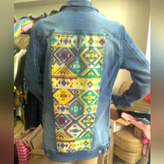 the back of a woman's jean jacket with colorful designs on it