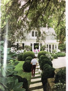 a man is walking down some steps in front of a house with trees and bushes