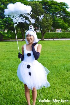 a woman dressed in a white dress and black gloves is holding an umbrella while standing in the grass