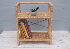 a wicker shelf with books and a potted plant sitting on top of it