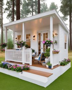 a small white house with flowers on the porch