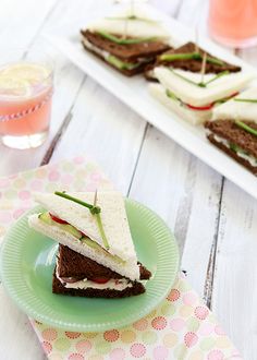 two plates with sandwiches on them sitting on a table next to glasses of water and lemonade