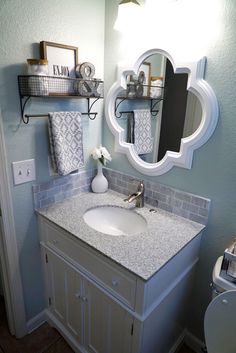 a white sink sitting under a bathroom mirror