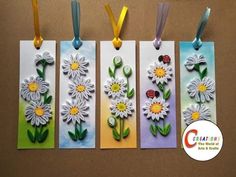 four bookmarks with paper flowers and ladybugs on them, hanging from ribbons