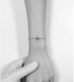 a person's wrist with a small bow tattoo on the left side of their arm