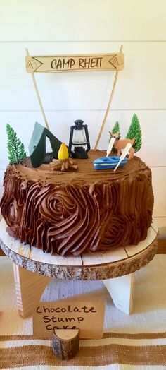 a cake with chocolate frosting and camping decorations on top is sitting on a table