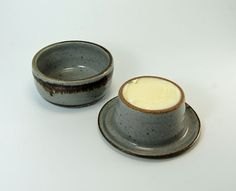 two small cups with saucers sitting next to each other on top of a white table