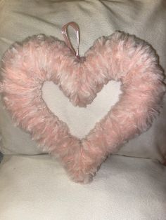 a pink heart shaped pillow sitting on top of a couch