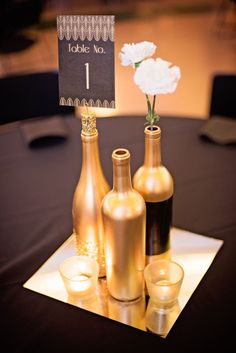 three wine bottles and two candles on a table with a sign that says to take no 1