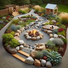 an outdoor fire pit surrounded by rocks and plants in the middle of a gravel path