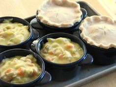 four cups filled with food sitting on top of a metal tray next to pies