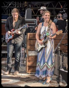 a man and woman playing guitars on stage