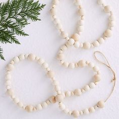 three white wooden beads on a string next to a pine branch