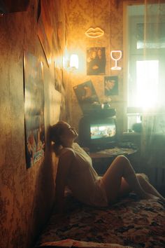 a woman laying on top of a bed next to a wall with pictures hanging up