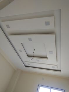 an empty room with white walls and square ceiling tiles on the ceiling, along with a window