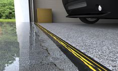 a car is parked in front of a building with water on the ground and yellow lines